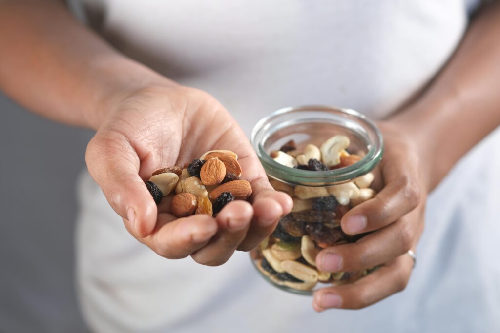 A person's hands holding a glass jar and a handful of assorted nuts, perfect for healthy snacking.