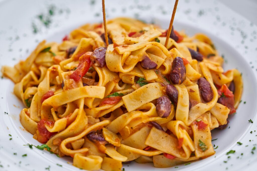 Close-up of delicious Italian pasta dish with kidney beans and rich sauce.