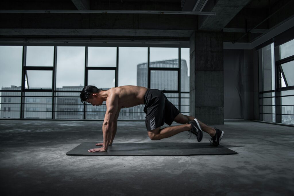 Fit man doing mountain climbers exercise inside a modern gym