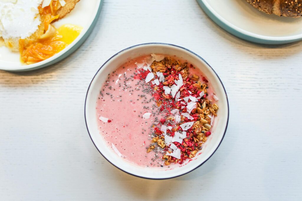 Delicious pink smoothie bowl with granola, chia seeds, and coconut flakes for a healthy breakfast.