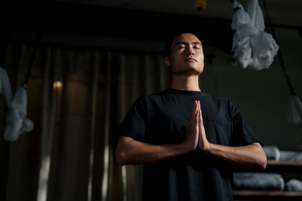 An adult male practicing meditation in a yoga studio, focusing on mindfulness and wellbeing.