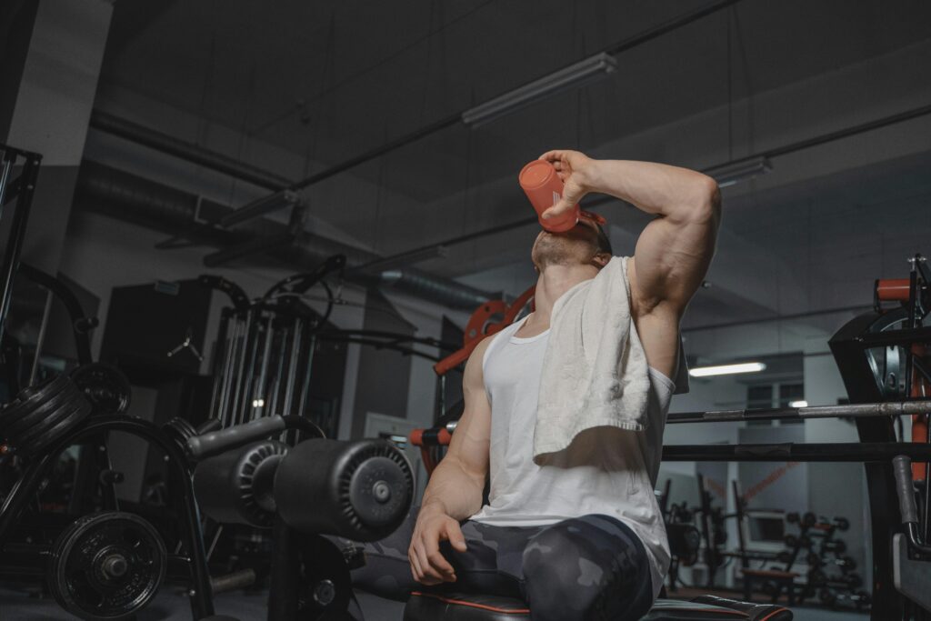 Strong man in gym drinking protein shake, emphasizing fitness and muscularity.