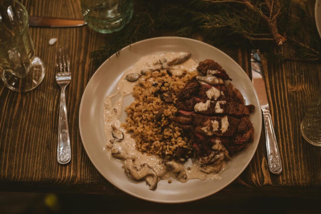 Top view of a rustic dinner with steak, rice, and mushrooms on a wooden table.