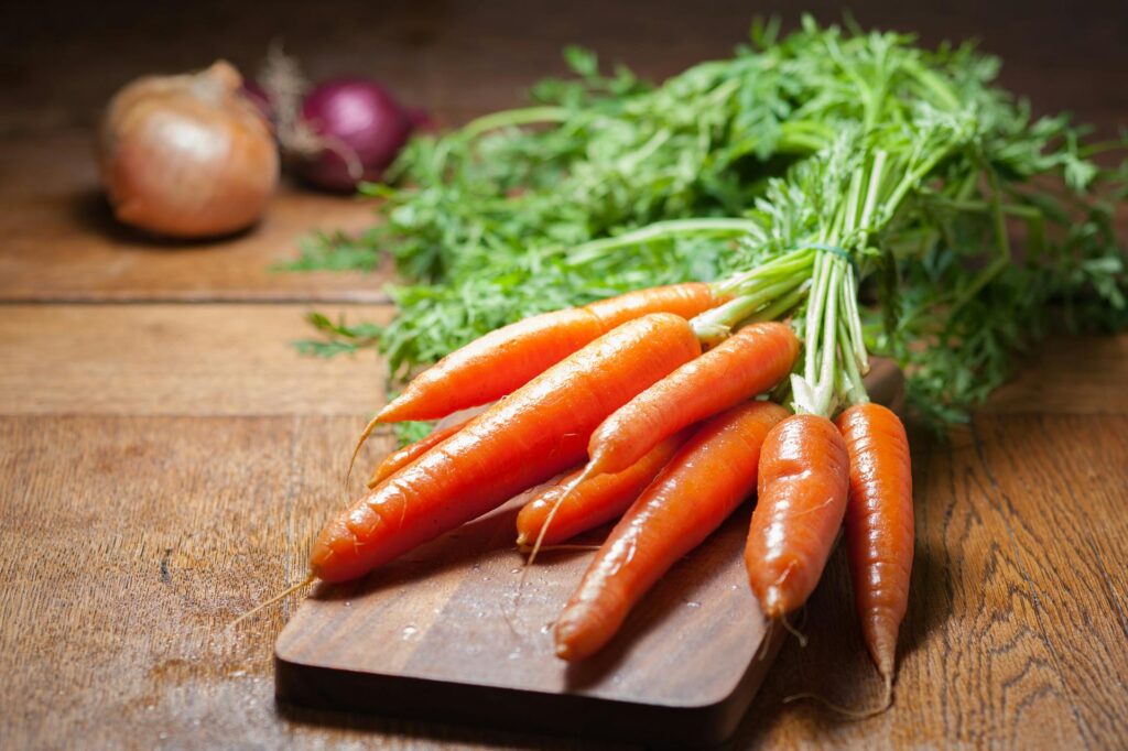 A bunch of fresh organic carrots on a wooden board, emphasizing healthy eating.