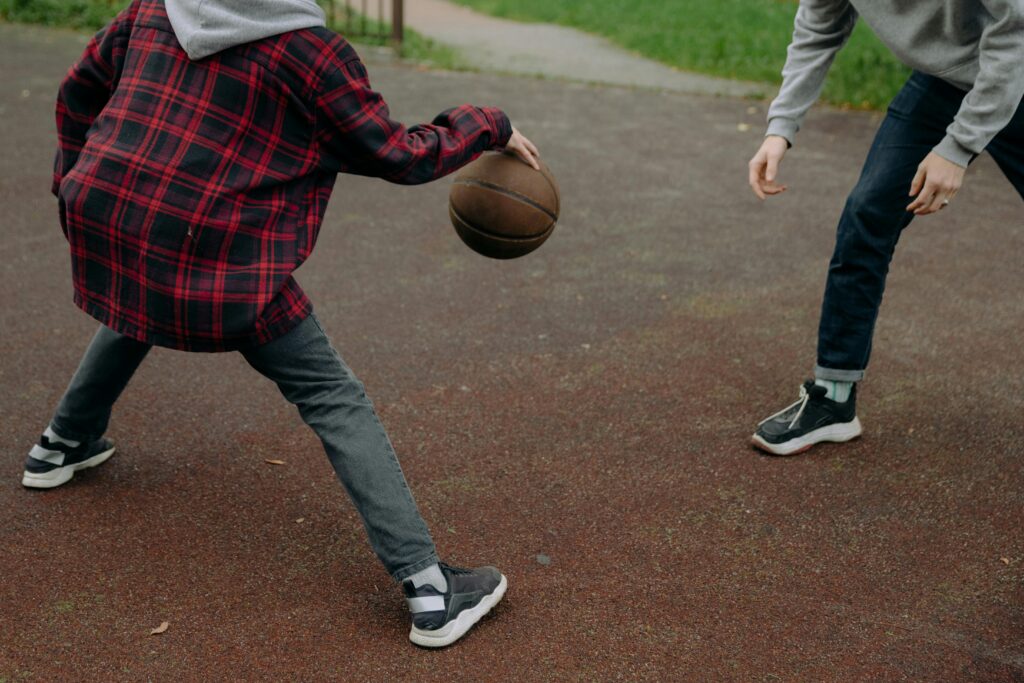 Two kids playing basketball on an outdoor court, enjoying a fun and active day.