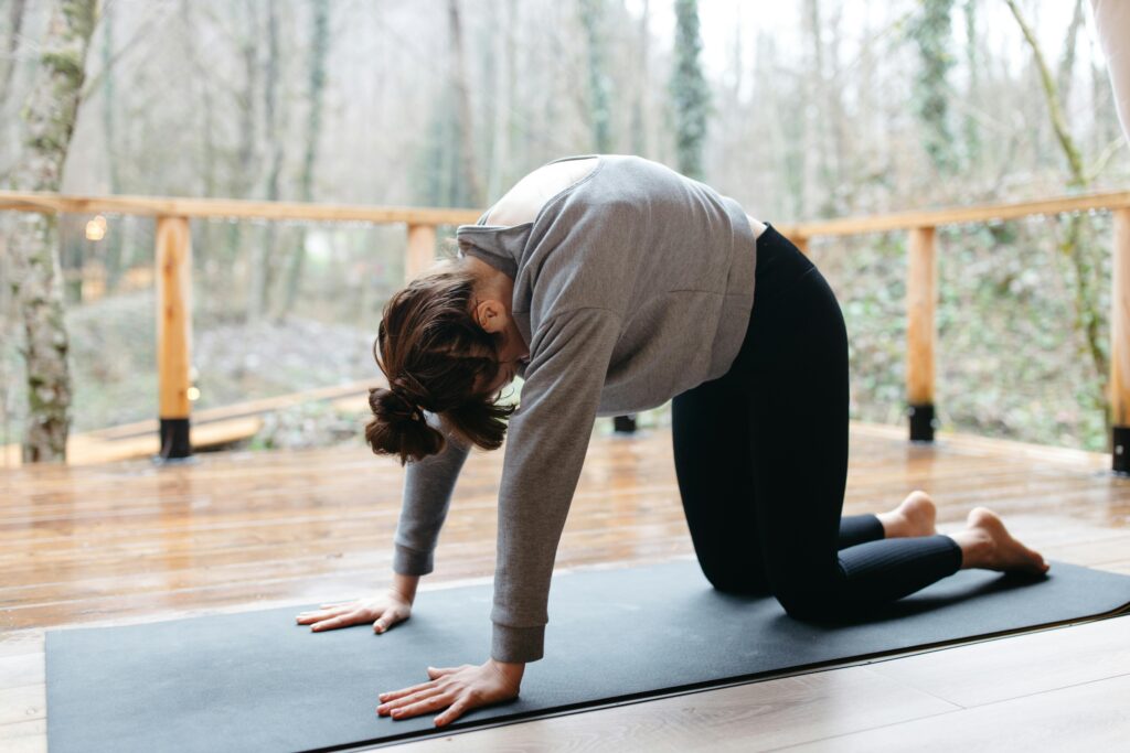 A woman doing yoga on a mat surrounded by trees, enhancing mindfulness and flexibility.