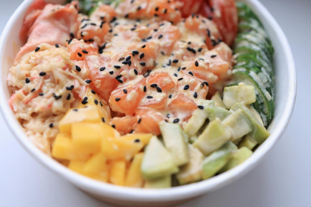 Delicious poke bowl featuring fresh salmon, avocado, mango, and sesame seeds.