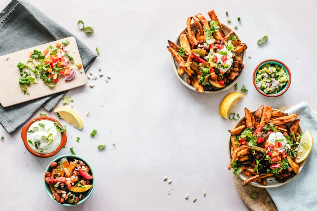 Colorful flat lay featuring sweet potato fries, guacamole, and fresh veggies, perfect for a healthy meal.