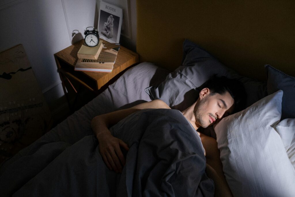 A man peacefully sleeping in bed with morning sunlight streaming in, creating a serene indoor scene.